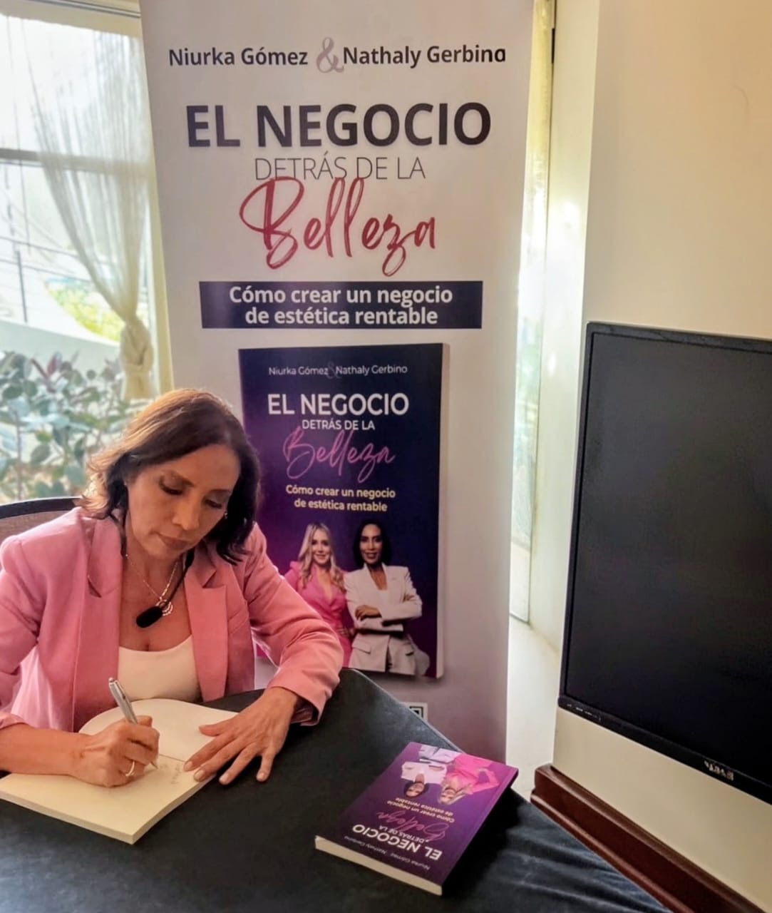 Niurka Gómez firmando el libro El negocio detrás de la belleza